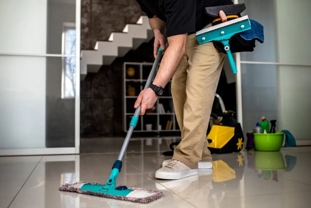 Person wischt einen Boden mit einem Mopp