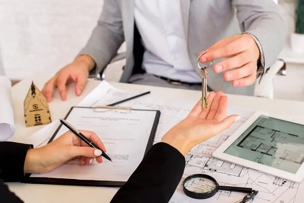 Schlüsselübergabe bei Immobilienvertrag mit Dokumenten.