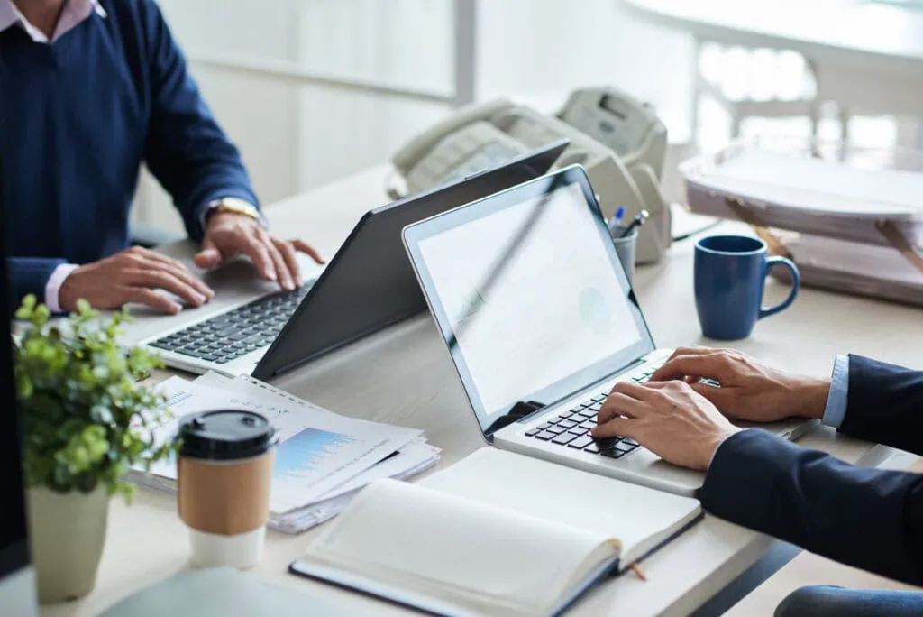Zwei Personen arbeiten an Laptops im Büro